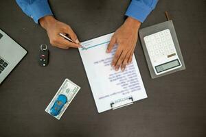 The car dealers of the car showrooms bring the car sales contract documents to the customers and explain the loan and interest rates to the customers before signing the sales contract for accuracy. photo