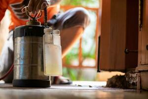 joven hombre elige a utilizar termita controlar productos quimicos ese son no tóxico a humanos mezclado con agua en tanque para pulverización a eliminar termitas habilitando joven hombre a rociar termita repelente por él mismo foto