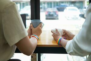 joven mujer lgbtq Pareja es teniendo café a ventana mostrador dentro café tienda y chateando felizmente. concepto de género igualdad para lgbt q grupo ese lata En Vivo felizmente juntos como Pareja. foto