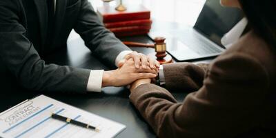 Business people compassionately holding hands and discussing contract papers with laptop and tabletat office photo