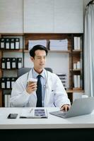 Medical technology concept. Asian Doctor working with mobile phone and stethoscope in modern office photo