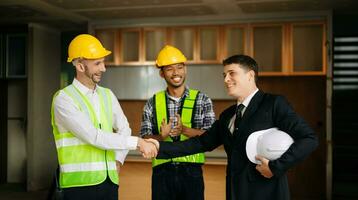 Engineers or architecture shaking hands at construction site for architectural project, holding safety helmet on their hands. successful cooperation photo