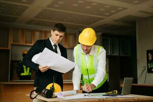 Engineers are discussing data working and laptop or tablet with architectural project at new construction site on big project. interior photo