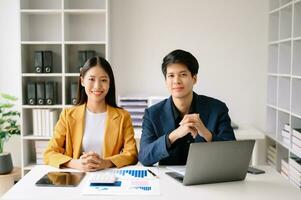 Two Asian business woman and man  discuss investment project working and planning strategy with tablet laptop computer in office. photo