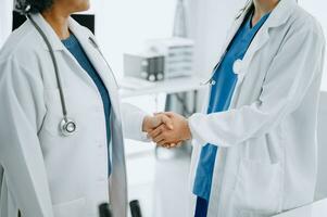 Doctor, handshake and partnership in healthcare, medicine or trust for collaboration, unity or support.Team of medical experts shaking hands in teamwork for or success in clinic or hospital photo