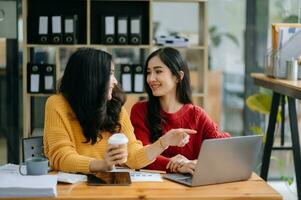 Two Attractive young Asian female college students working on the school project using laptop computer and tablet together, enjoy talking photo