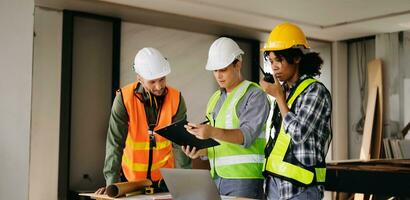 Contractor and architect looking at plan, tablet, laptop and talking about working on big project. Building in construction process interior. team work photo