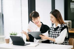 Two Asian business workers talking on the smartphone and using laptop at the modern office. photo