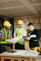 Engineers are discussing data working and laptop or tablet with architectural project at new construction site on big project. interior photo