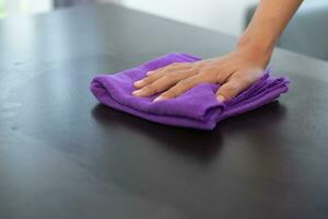 Cleaning staff is wiping cloth with cleaner and disinfectant on the surface of table to make the table clean with cleaning products and free from germs clinging to surface of the table in living room. photo