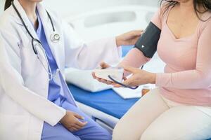 The doctor is using a blood pressure monitor on an elderly patient to check whether the blood pressure is abnormally high or not because hypertension often happens to the elderly and is dangerous. photo