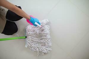 Cleaning staff is wiping cloth with cleaner and disinfectant on the surface of floor to make the floor clean with cleaning products and free from germs clinging to surface of the floor in living room. photo