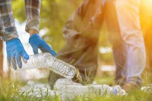 men collect plastic bottles on lawns and walkways in park and put them in bags to help keep them clean They can also collect plastic bottles for recycling. reducing environmental problems by recycling photo
