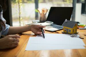The real estate agent is reviewing the documents and calculating the interest rate to inform the tenant of the monthly installments to be paid before the real estate purchase agreement is finalized. photo