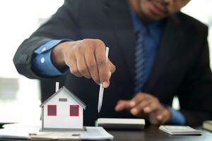 The real estate agent is reviewing the documents and calculating the interest rate to inform the tenant of the monthly installments to be paid before the real estate purchase agreement is finalized. photo