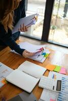 secretary searches through stacked documents on desk in office to find lease within stacked documents just before meeting. concept difficulty in finding hire purchase contract from stacked documents photo