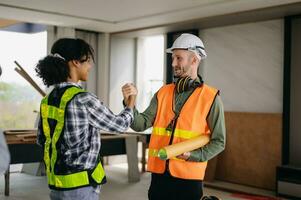 Construction team shake hands greeting start new project plan behind yellow helmet on desk in office center to consults about their building project. photo