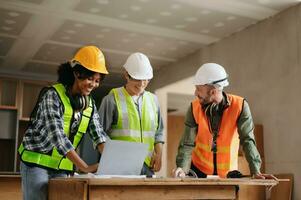 Architect caucasian man and woman working with colleagues mixed race in the construction site. Architecture engineering on big project. Building in construction process interior. photo