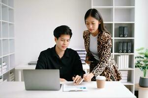 Two  Asian business  man and woman workers talking on the smartphone and using laptop Professionals in Teamwork  Finance, Marketing, and Success photo