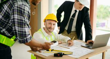 Architect caucasian man working with colleagues mixed race in the construction site. Architecture engineering on big project. Building in construction process photo