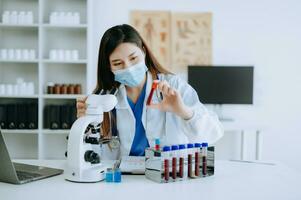 Young scientists conducting research investigations in a medical laboratory, a researcher in foreground is using a microscope in laboratory for medicine. photo