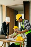 Architect caucasian man working with colleagues mixed race in the construction site. Architecture engineering on big project. Building in construction process photo