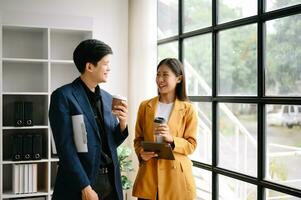 Two  Asian business  man and woman workers talking on the smartphone and using laptop Professionals in Teamwork  Finance, Marketing, and Success photo