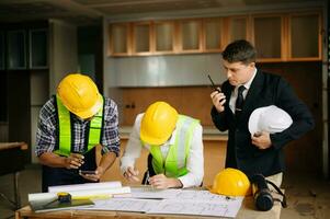 Contractor and architect looking at plan, tablet, laptop and talking about working on big project. Building in construction process photo