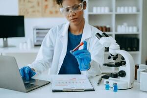 Modern medical research laboratory. African female scientist working with micro pipettes analyzing biochemical samples, advanced science chemical laboratory for medicine. photo