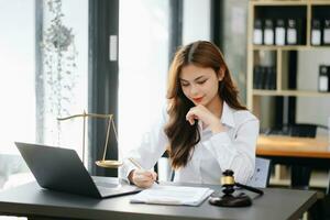 Beautiful asian woman lawyer working and gavel, tablet, laptop in front, Advice justice and law concept. photo