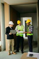 Contractor and architect looking at plan, tablet, laptop and talking about working on big project. Building in construction process photo