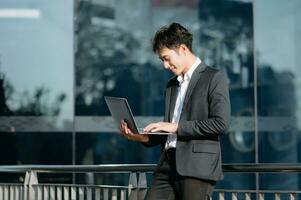 joven asiático negocio hombre trabajando a fuera de negocio centrar con computadora portátil, tableta, teléfono inteligente y tomando notas en el papel. foto
