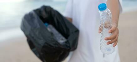 ahorrar agua. los voluntarios recogen basura en la playa y las botellas de plástico son difíciles de descomponer para evitar dañar la vida acuática. tierra, ambiente, planeta verde, reducir el calentamiento global, salvar el mundo foto