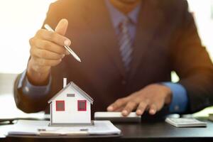 The real estate agent is reviewing the documents and calculating the interest rate to inform the tenant of the monthly installments to be paid before the real estate purchase agreement is finalized. photo