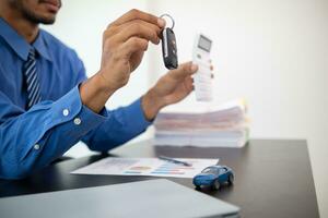 The car showroom car dealer handed over the keys to the customer after the purchase contract was finalized. The concept of buying and selling car with a trusted dealer for peace of mind. photo