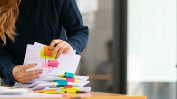 secretary searches through stacked paperwork on desk in office to find lease within stacked paperwork just before meeting. concept difficulty in finding hire purchase contract from stacked paperwork photo