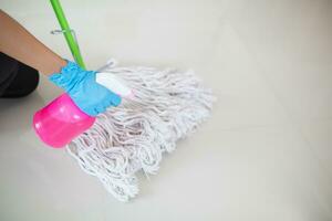 Cleaning staff is wiping cloth with cleaner and disinfectant on the surface of floor to make the floor clean with cleaning products and free from germs clinging to surface of the floor in living room. photo