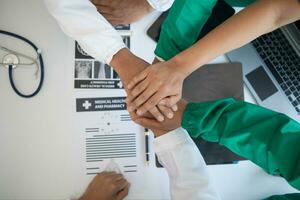 The medical team joins hands after the meeting and discusses the treatment of severely ill patients and can come to a conclusion on the surgical treatment of the patient. Medical team meeting concept photo