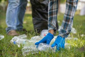 men collect plastic bottles on lawns and walkways in park and put them in bags to help keep them clean They can also collect plastic bottles for recycling. reducing environmental problems by recycling photo