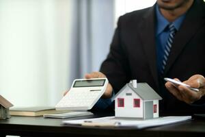 The real estate agent is reviewing the documents and calculating the interest rate to inform the tenant of the monthly installments to be paid before the real estate purchase agreement is finalized. photo