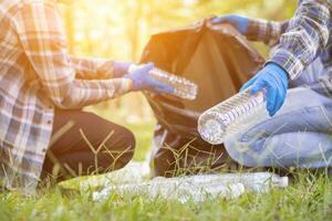 men collect plastic bottles on lawns and walkways in park and put them in bags to help keep them clean They can also collect plastic bottles for recycling. reducing environmental problems by recycling photo