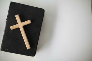 Cross represents God placed on Bible which is teaching of God according to Christian faith. cross and Bible were placed on table in room as they were prepared for prayers to God by faith. photo