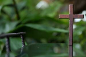 cross representing God in Christianity is placed on mirror and its reflection can be seen on blurred background of nature. cross on background is blurred and there is Copy Space on side for text. photo