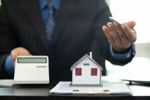 The real estate agent is reviewing the documents and calculating the interest rate to inform the tenant of the monthly installments to be paid before the real estate purchase agreement is finalized. photo