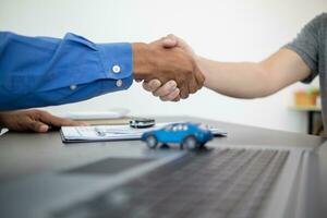 car dealer shook hands with buyer as sign of successful deal and a thank you after the car purchase contract was signed. concept of a handshake to express gratitude after a successful sale contract. photo