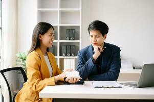 Two Asian business woman and man  discuss investment project working and planning strategy with tablet laptop computer in office. photo