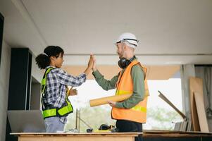 Construction team shake hands greeting start new project plan behind yellow helmet on desk in office center to consults about their building project. photo