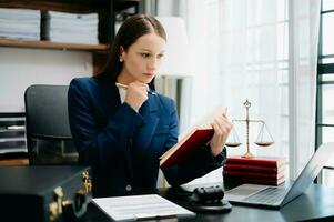 justice and law concept. Female judge in a courtroom  the gavel, working with smart phone and laptop and digital tablet computer on black  table photo