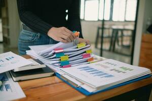 secretary searches through stacked documents on desk in office to find lease within stacked documents just before meeting. concept difficulty in finding hire purchase contract from stacked documents photo
