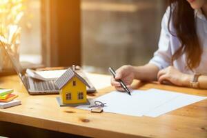 The real estate agent is reviewing the documents and calculating the interest rate to inform the tenant of the monthly installments to be paid before the real estate purchase agreement is finalized. photo